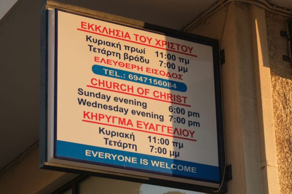 A sign notes the Greek and English meeting times for the Glyfada Church of Christ.