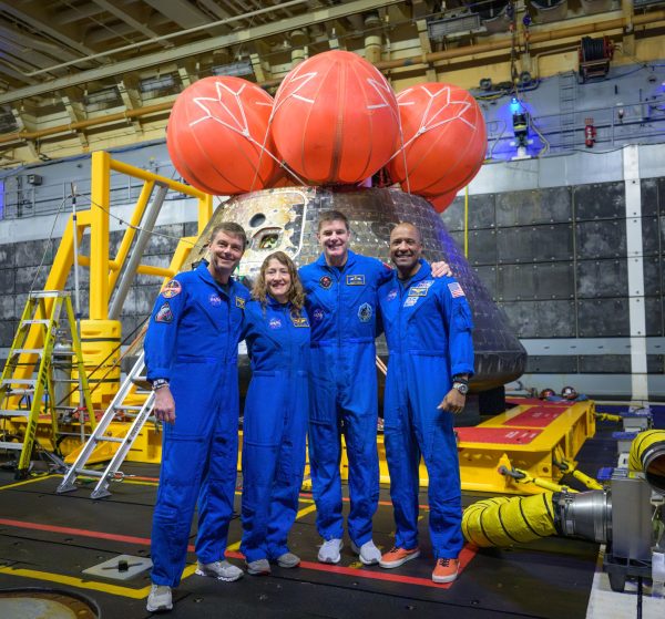 Astronauts Reid Wiseman, Christina Koch, astronaut Jeremy Hansen and Victor Glover pose for a group photo after viewing the Orion spacecraft in the well deck of USS John P. Murtha
