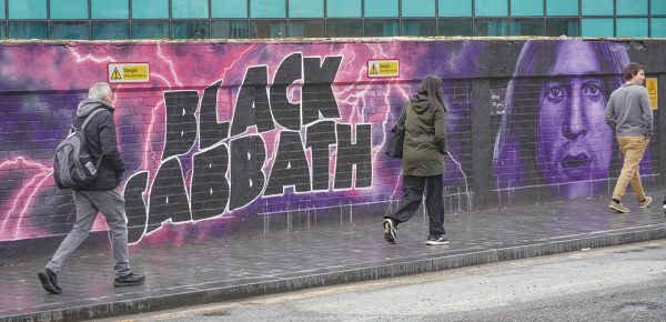 People in Birmingham walk past a tribute mural for Black Sabbath and its frontman, the late Ozzy Osbourne.
